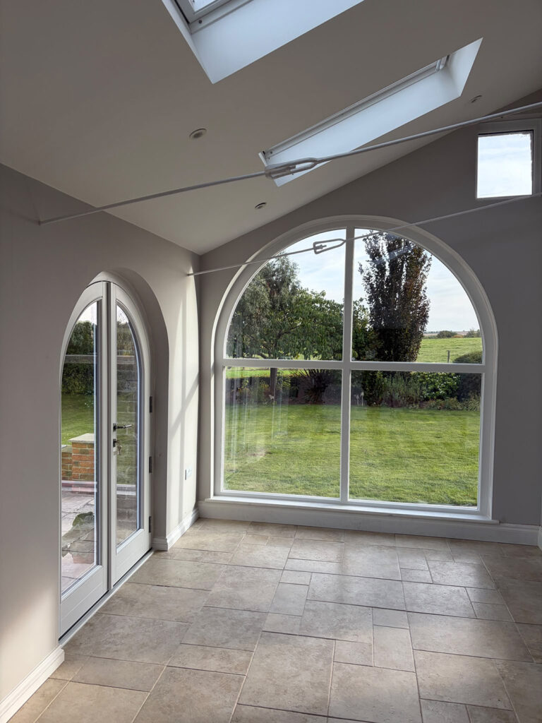 a very large arched fixed casement window in an open empty room