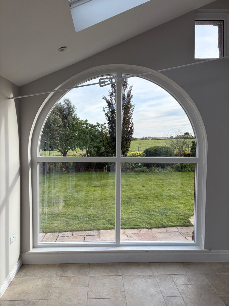 a very large arched fixed casement window in an open empty room