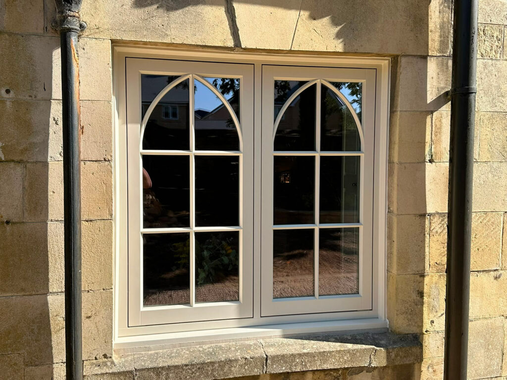 a casement window on a yellow stony property with gothic glazing bars
