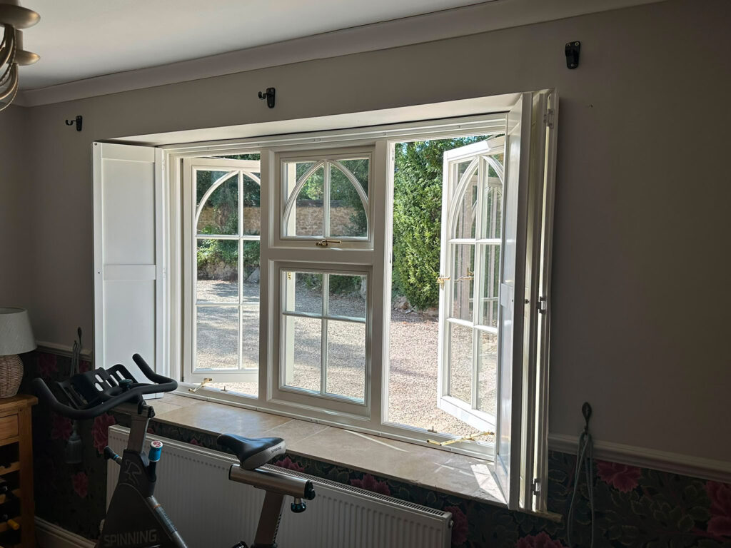 a triple casement window with open outer sashes and gothic glazing bars