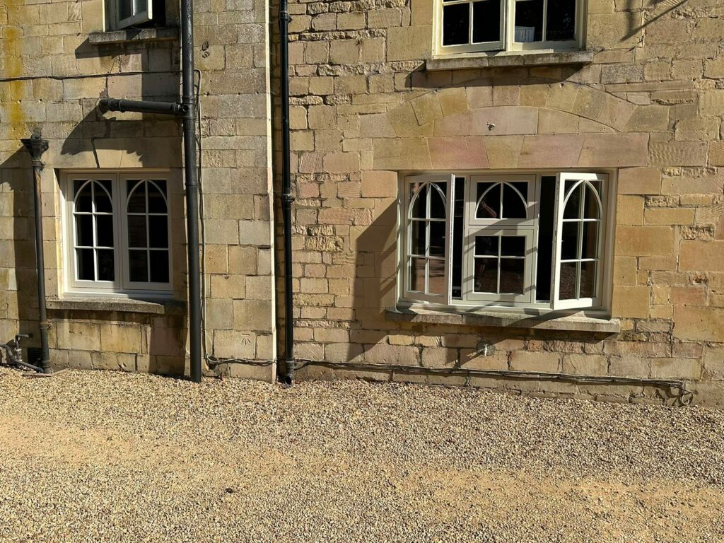 a casement window on a yellow stony property with gothic glazing bars