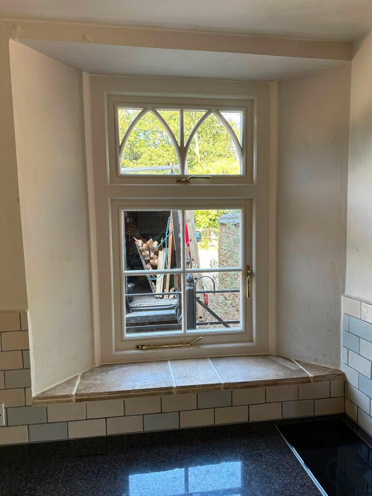 a casement window with a fanlight featuring gothic glazing bars