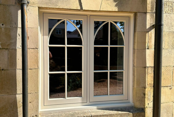a casement window on a yellow stony property with gothic glazing bars