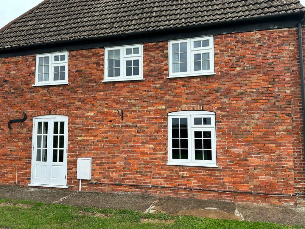 a red brick house with white stormproof casement windows