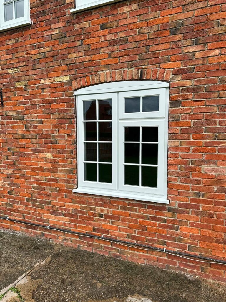 white stormproof casement windows with georgian bars on a red brick house