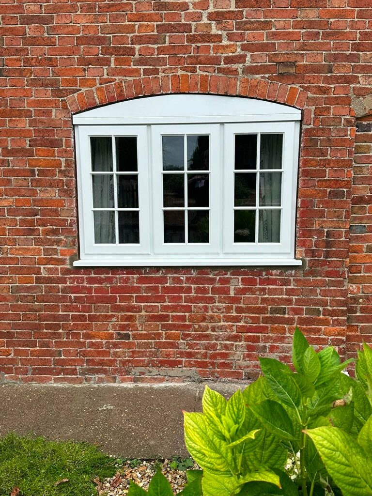 white stormproof casement windows with georgian bars on a red brick house