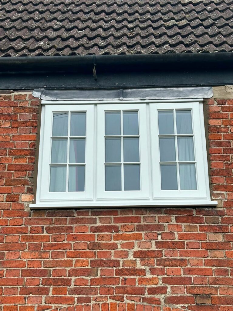 white stormproof casement windows with georgian bars on a red brick house