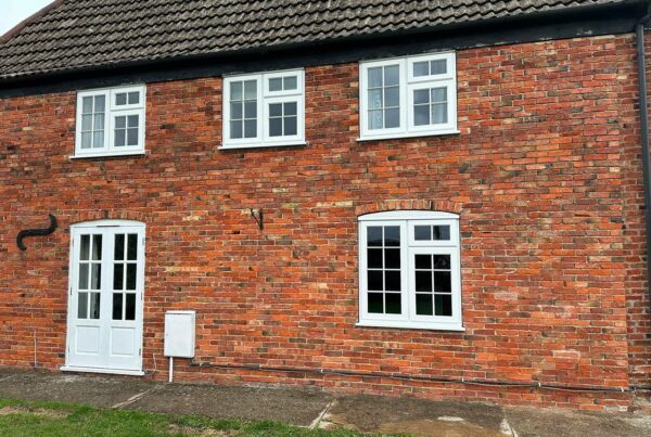 a red brick house with white stormproof casement windows